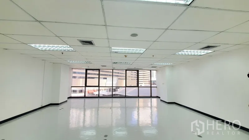 Office Space for rent in Watthana, Bangkok - Bright open-plan office with glossy floor, grid ceiling lights, and a wall of large windows with city views.
