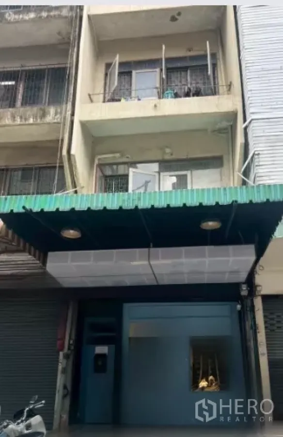 Shophouse for rent in Watthana, Bangkok - Three-storey shophouse facade with green awning and a modern ground-floor frontage on a busy row.