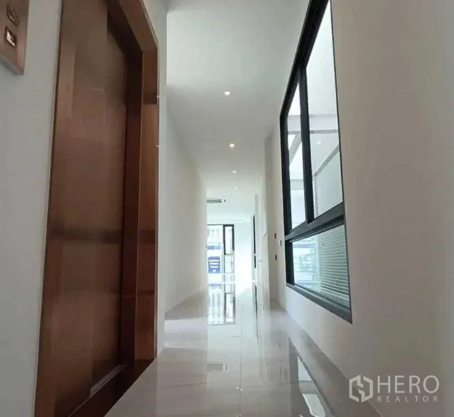 Home Office for rent in Suan Luang, Bangkok - Clean hallway featuring a lift, recessed lighting and glossy white tiles.
