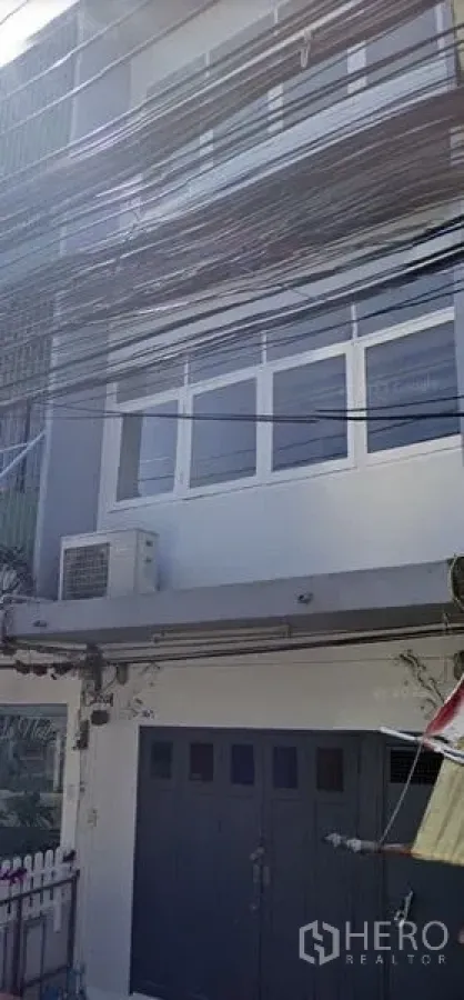 Shophouse for rent in Watthana, Bangkok - Three-storey shophouse exterior with wide front doors, windows and an air-conditioning unit.