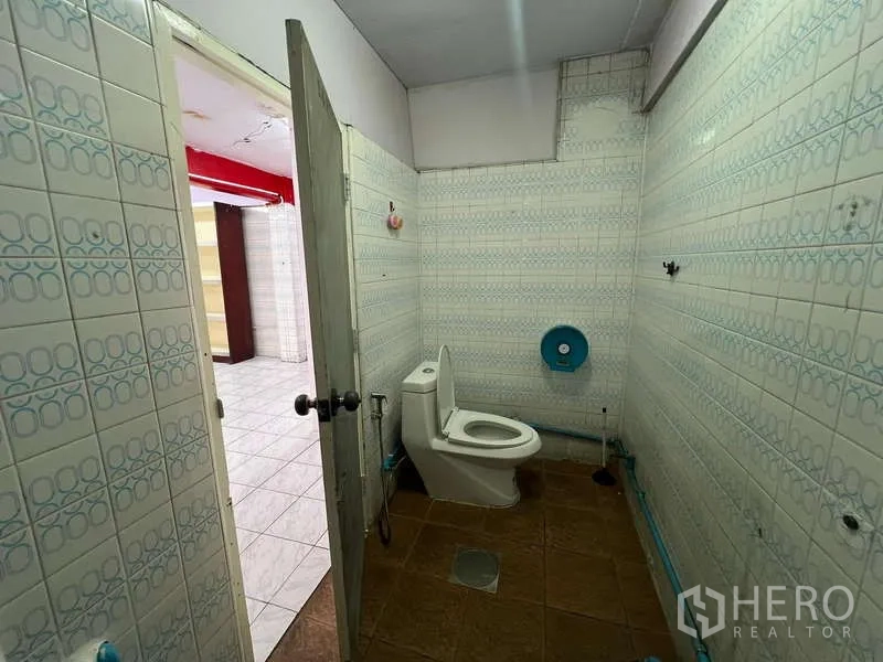 Shophouse for rent in Suan Luang, Bangkok - Restroom with toilet and tiled walls next to the shop floor.