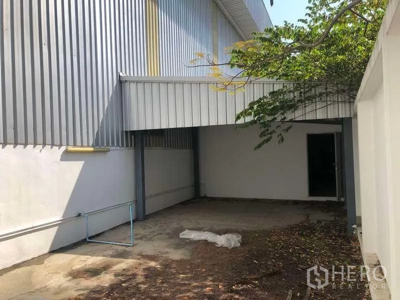 Factory for rent or sale in Samut Prakan - Covered side yard beside the factory with metal awning and service doorway.