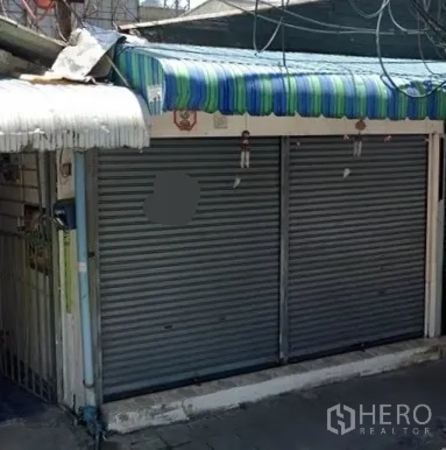 零售空间 出租在Watthana, Bangkok - 街边店铺外观，双金属卷帘门与条纹雨棚，临近小巷。