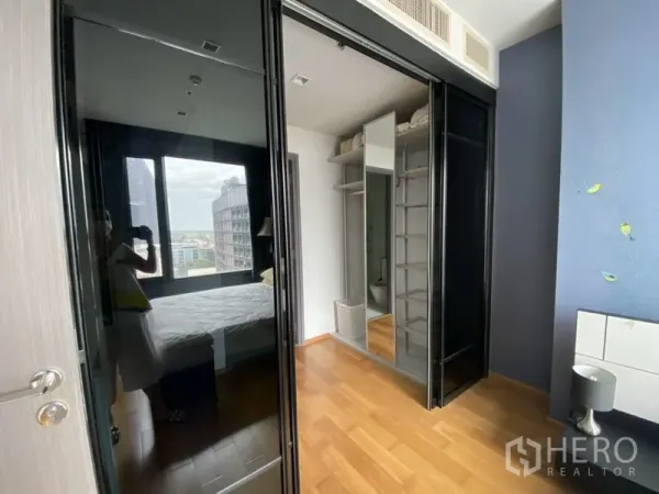 Condominium for rent in Khlong Toei, Bangkok - Walk-in closet with sliding glass wardrobe doors and custom shelving beside the bedroom