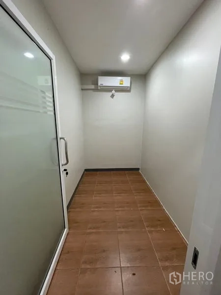 Home Office for rent in Chatuchak, Bangkok - Small glass-enclosed office with brown tile floor and air conditioner.
