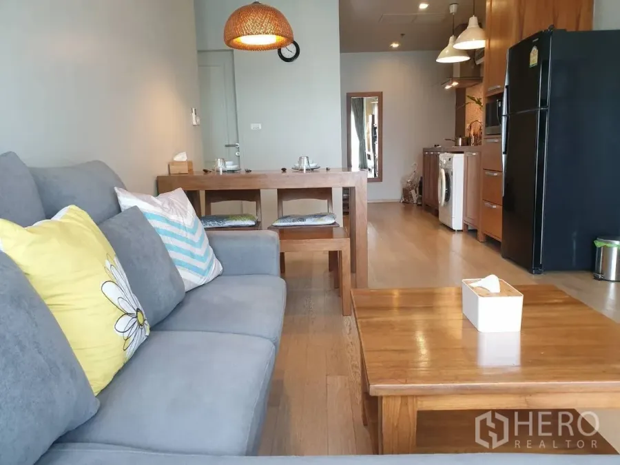 Condominium for rent or sale in Bangkok - Cozy gray sofa and dining set facing a compact kitchen in the open living space.