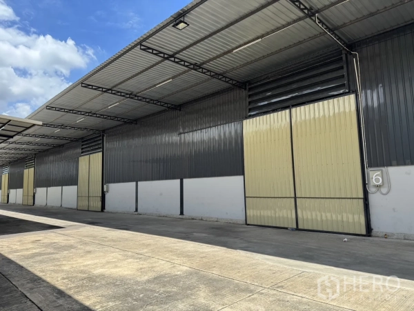 Warehouse for rent in Phra Nakhon Si Ayutthaya, Phra Nakhon Si Ayutthaya - Warehouse exterior with numbered bay and beige sliding door under extended roof for weather-protected loading.