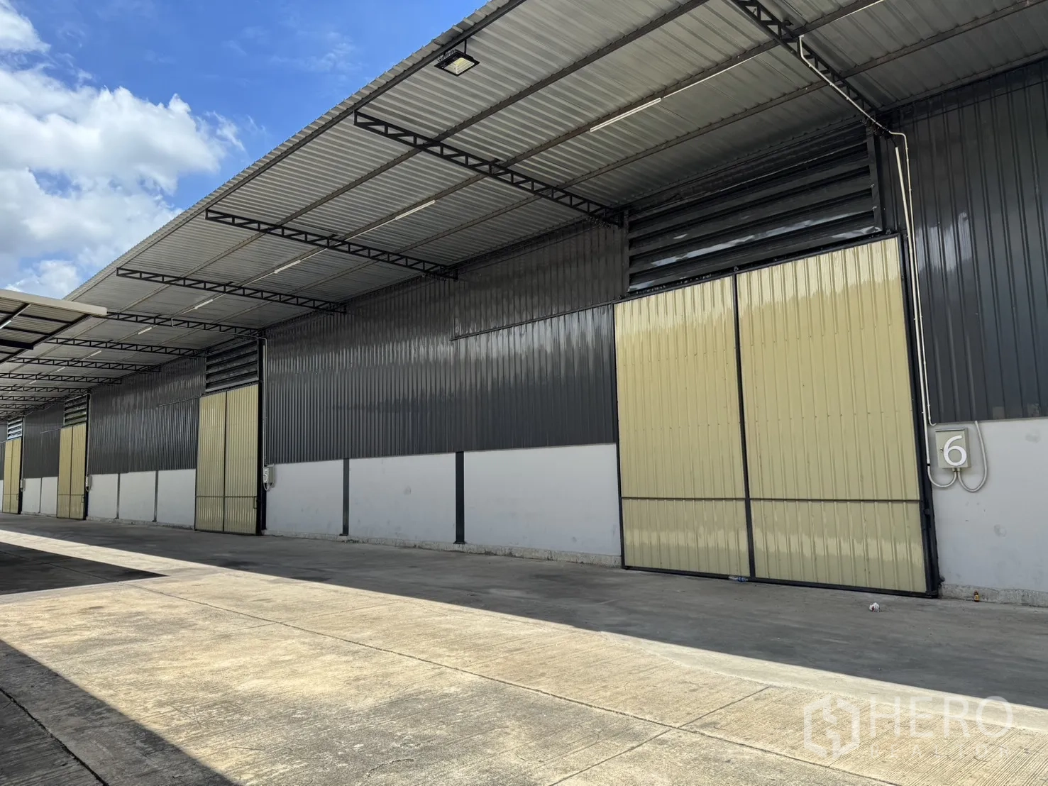 Warehouse for rent in Phra Nakhon Si Ayutthaya, Phra Nakhon Si Ayutthaya - Warehouse exterior with numbered bay and beige sliding door under extended roof for weather-protected loading.