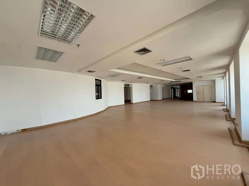 Office Space for rent in Chatuchak, Bangkok - Long open workspace lined with windows and fluorescent grid lighting.