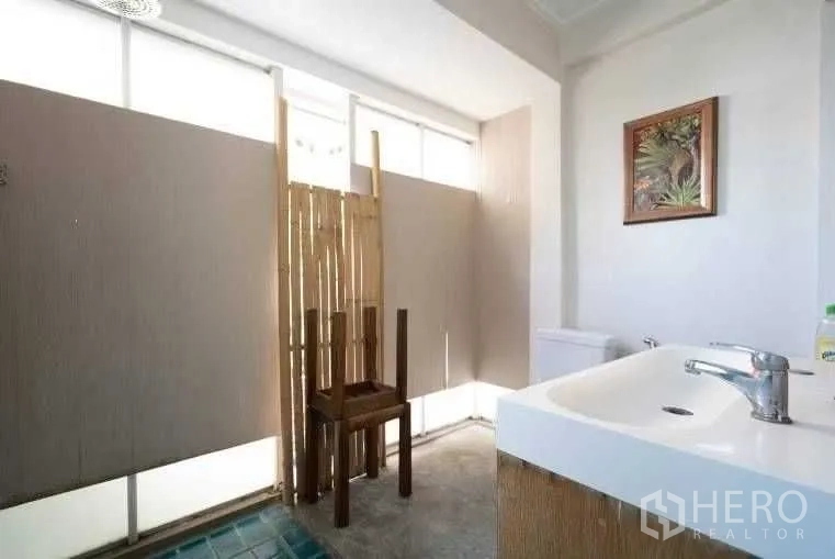 Detached House for rent in Khlong Toei, Bangkok - Second bathroom with sink, toilet, frosted windows, and bamboo privacy screen.