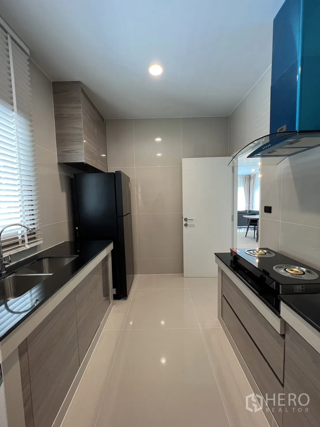 Detached House for rent in Bang Kapi, Bangkok - Kitchen view with black countertops, ample cabinets and refrigerator.