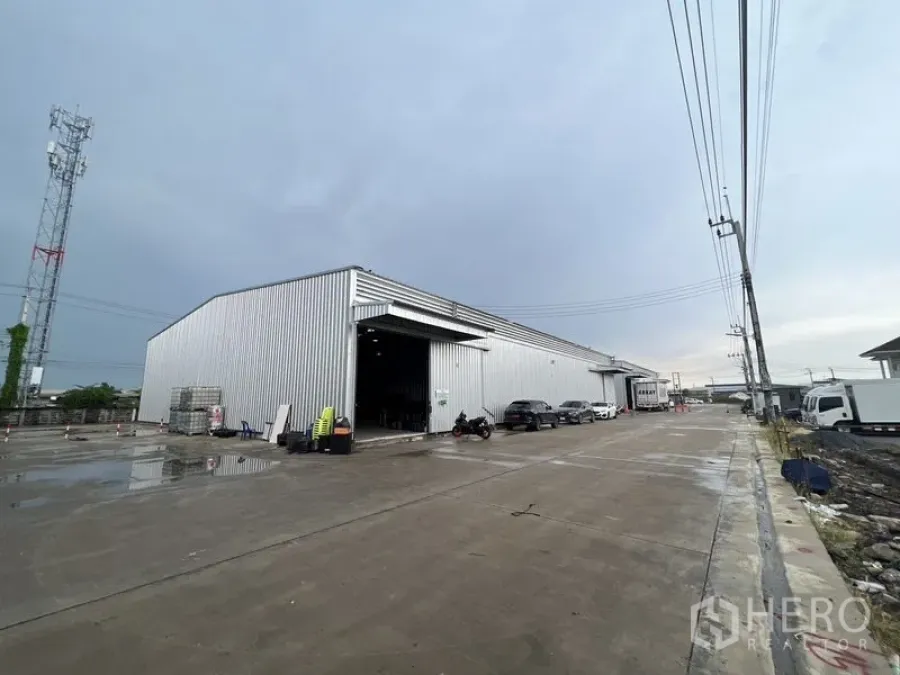 Warehouse for rent in Lat Krabang, Bangkok - Large metal-clad warehouse exterior with open loading bay and wide concrete driveway suitable for container trucks.