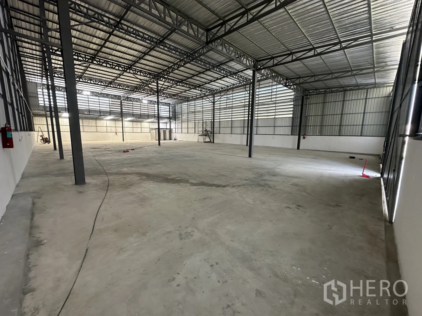 Warehouse for rent in Bang Kapi, Bangkok - Spacious warehouse interior with high steel truss roof, clear-span concrete floor, and natural light panels.