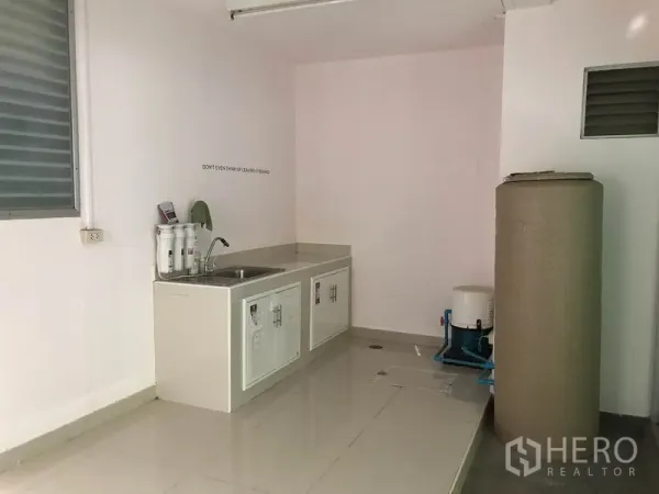 Townhouse for rent in Suan Luang, Bangkok - Minimal Thai kitchen with sink, base cabinets and water filtration beside a utility tank.