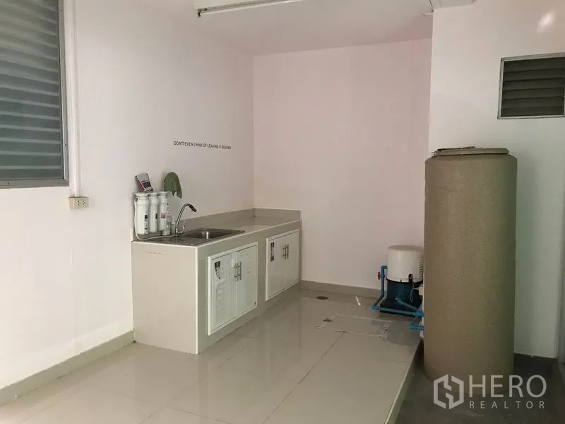 Townhouse for rent in Suan Luang, Bangkok - Minimal Thai kitchen with sink, base cabinets and water filtration beside a utility tank.
