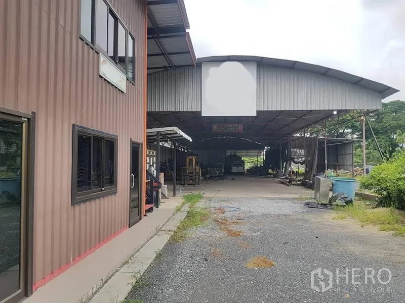 Warehouse for rent in Sai Noi, Nonthaburi - Front view of the warehouse and office block with a wide gravel driveway.