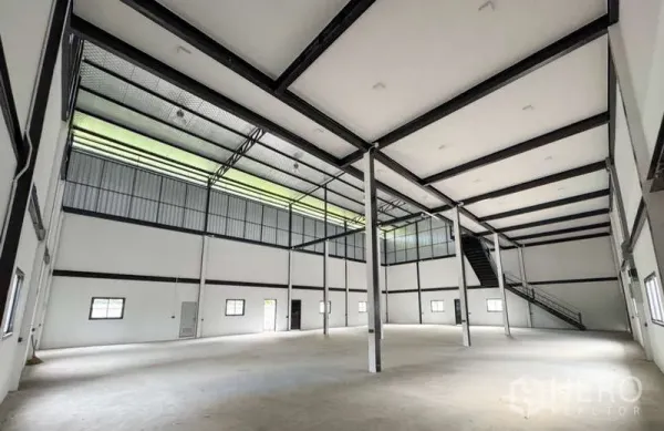 Warehouse for rent in Bang Phli, Samut Prakan - Bright high‑clearance warehouse hall with skylight panels, steel columns and side staircase.