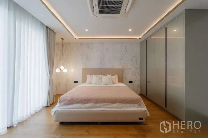 Townhouse for rent or sale in Watthana, Bangkok - Master suite with king bed, pendant lights, and sheer drapes.