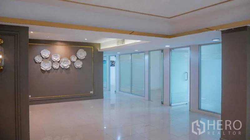 Office Space for rent in Chatuchak, Bangkok - Bright office reception with polished tile floors, feature wall art, and frosted‑glass rooms along the side.