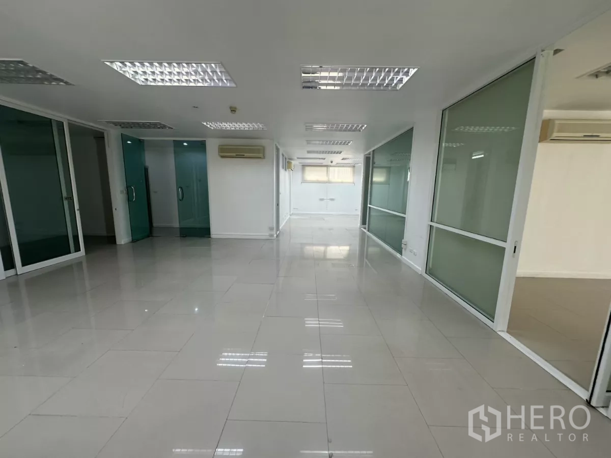 办公空间 出租在Huai Khwang, Bangkok - 走廊视角的办公室，多处玻璃隔间与白色瓷砖地面。