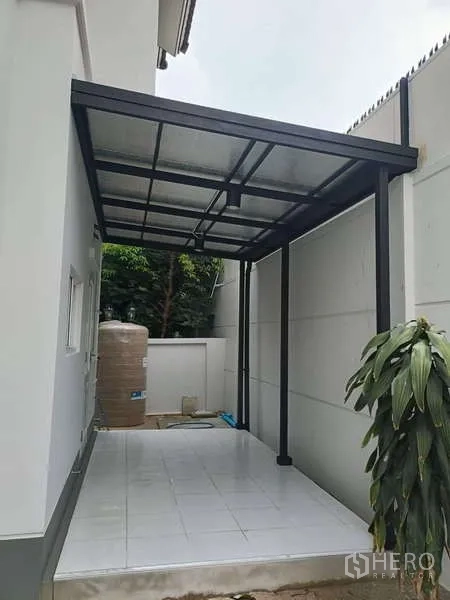 Detached House for rent in Bang Kapi, Bangkok - Covered tiled patio or carport with metal frame roof and water tank.