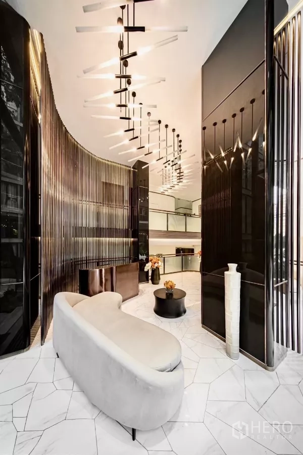 Condominium for rent in Khlong Toei, Bangkok - Luxurious lobby with sculptural sofa and dramatic chandeliers.