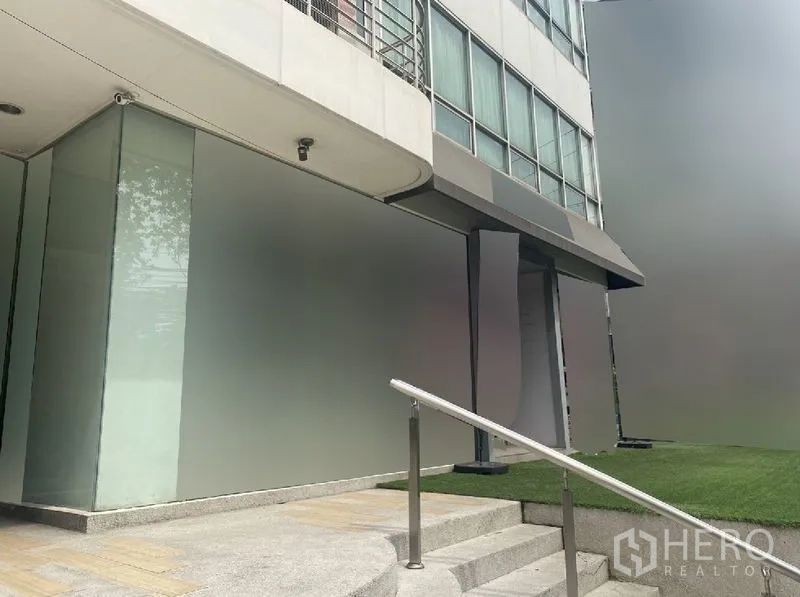 Retail Space for rent in Watthana, Bangkok - Corner retail facade with glass walls, ramped steps, and a small lawn beside the entrance.