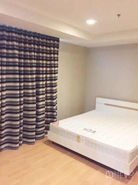 Condominium for rent in Khlong Toei, Bangkok - Guest bedroom with double bed and striped blackout curtains.