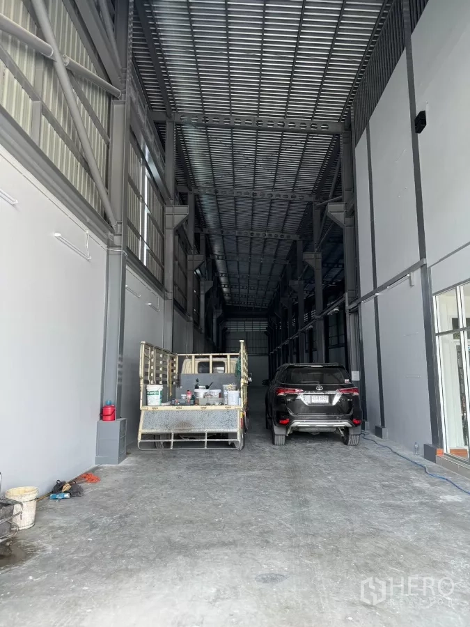 Warehouse for rent in Bang Khun Thian, Bangkok - Deep warehouse bay under a metal roof with space for vehicles and pallets.