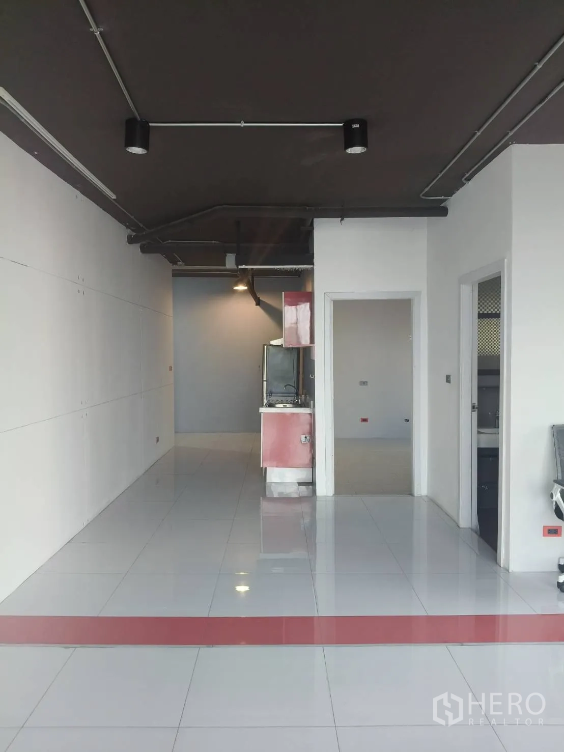 Office Space for rent in Khlong Toei, Bangkok - Open-plan office with white tiled floor, exposed black ceiling and a compact kitchenette at the rear.