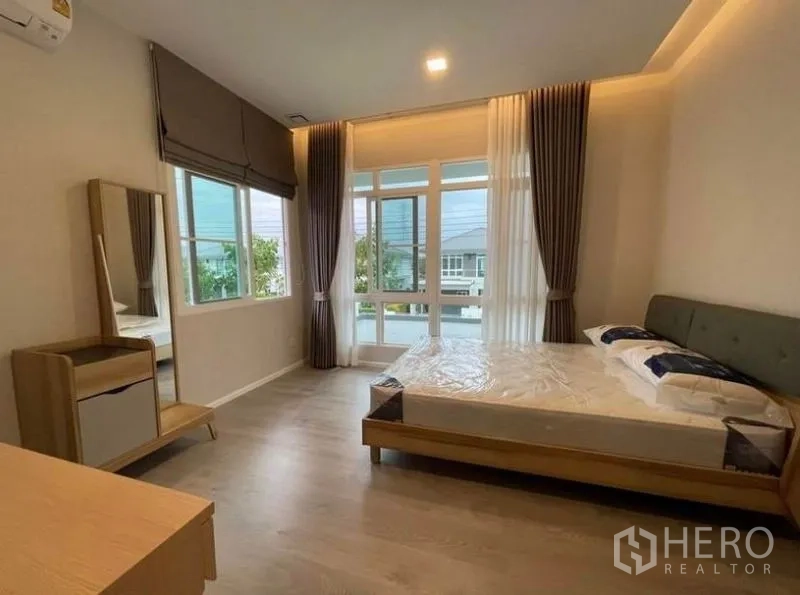 Detached House for rent in Prawet, Bangkok - Sunlit secondary bedroom with large corner windows and contemporary furnishings.