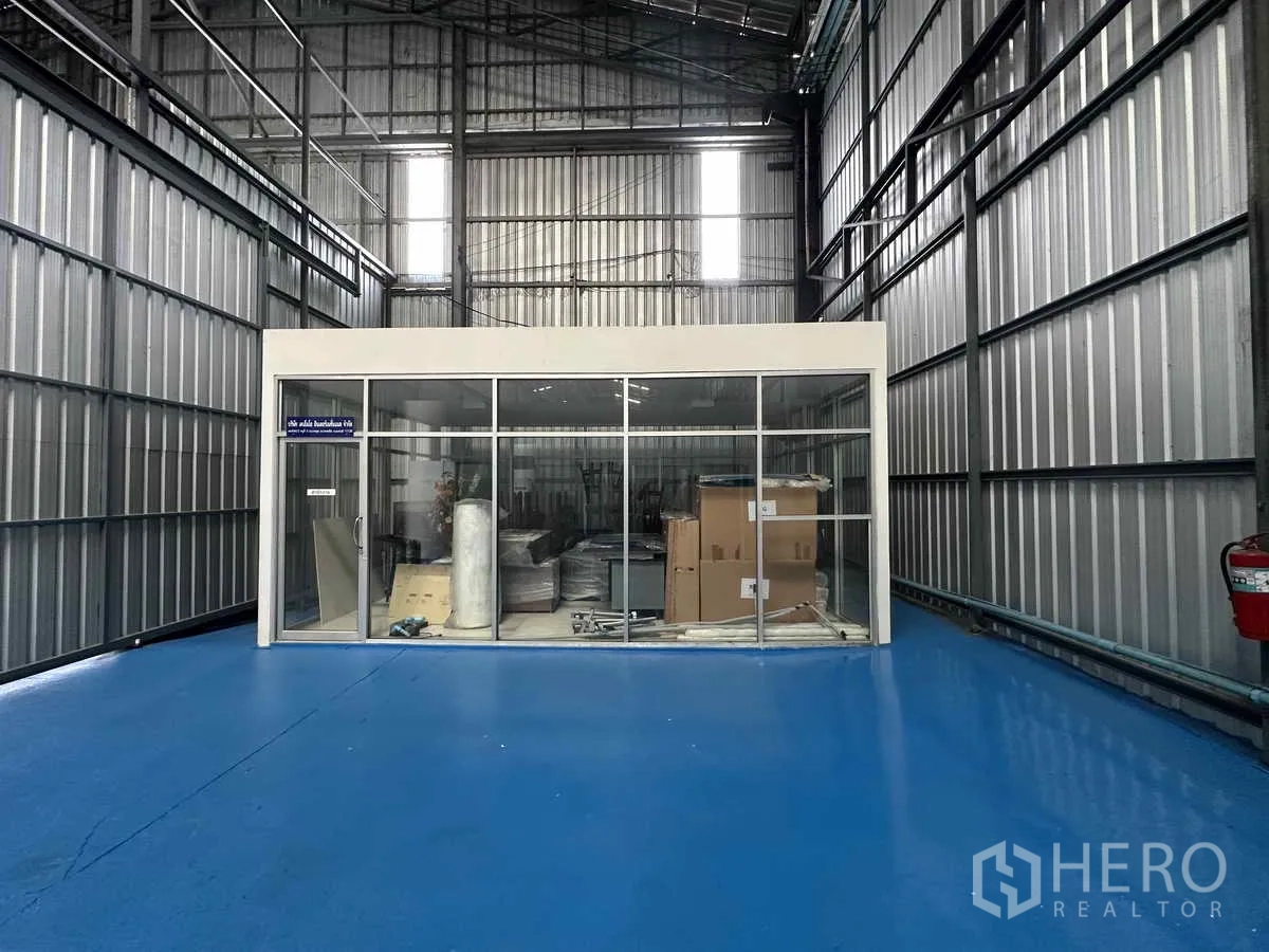 货栈 出租在Pak Kret, Nonthaburi - 高挑仓库空间，蓝色地坪与玻璃围合办公室。