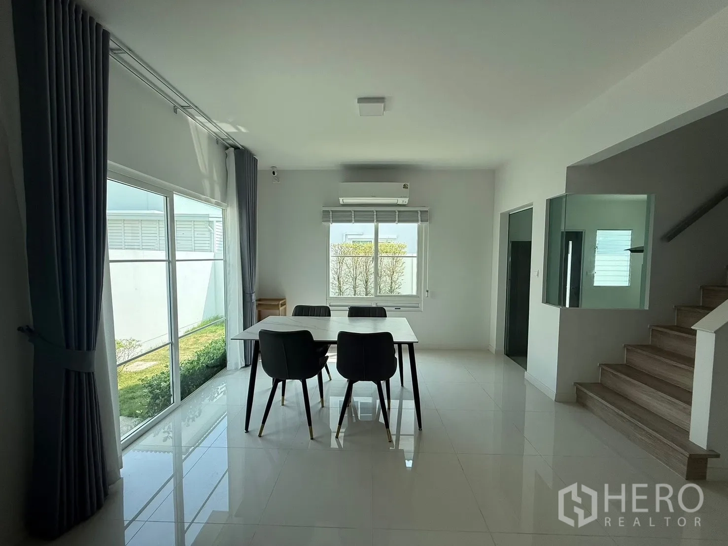 Detached House for rent in Bang Phli, Samut Prakan - Dining area beside large windows with garden views and stairs to the upper floor.