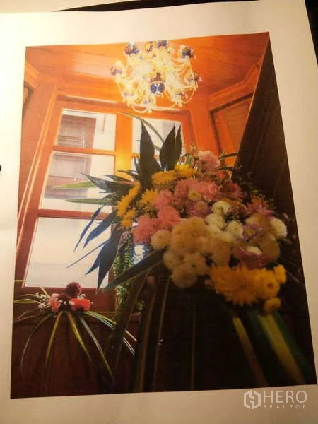 Townhouse for rent in Khlong Toei, Bangkok - Stairwell window with chandelier and fresh flower arrangement.