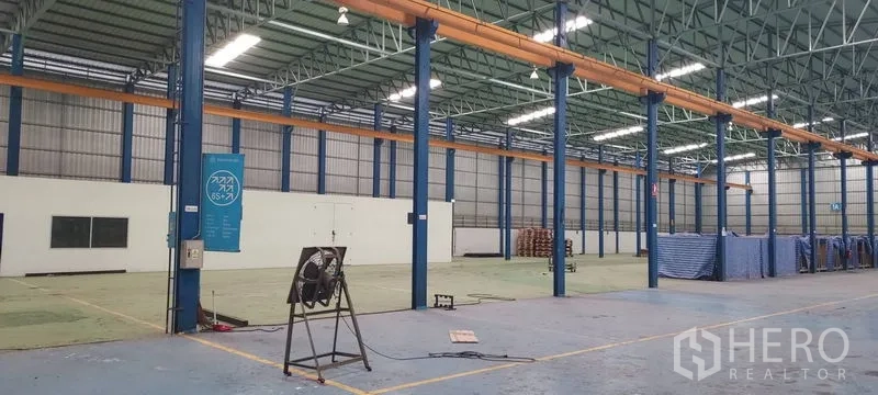 Factory for rent in Phra Pradaeng, Samut Prakan - Warehouse interior showing blue steel columns and overhead crane rails.