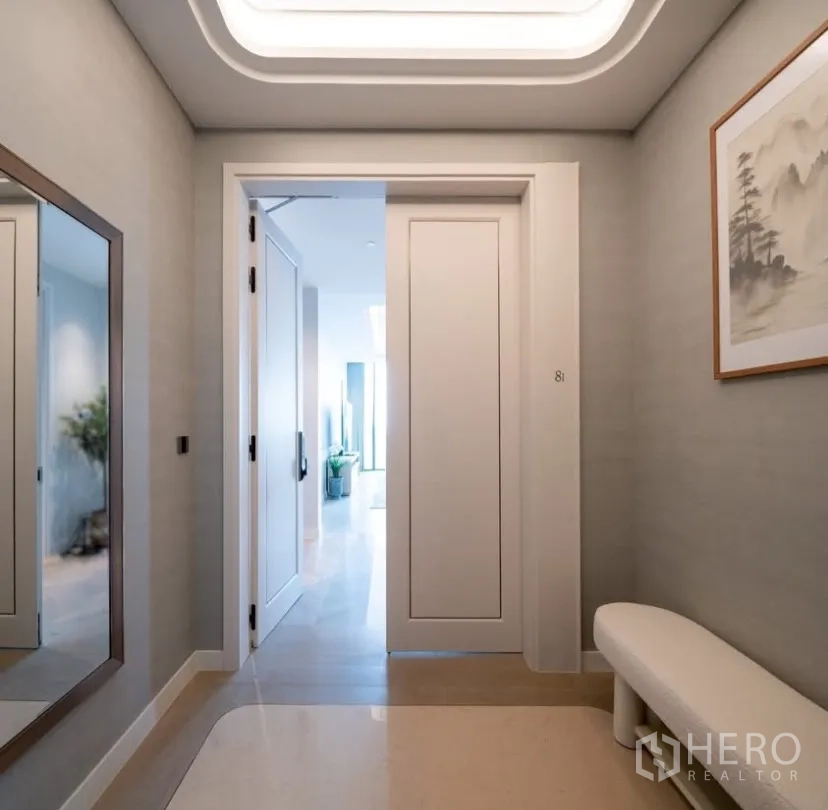 Condominium for rent or sale in Pathum Wan, Bangkok - Elegant foyer with large mirror, wall art and doorway to the bright living spaces.