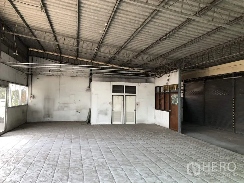 Warehouse for rent in Khlong Luang, Pathum Thani - Open-plan interior with tiled floor, steel truss roof and small office doors.