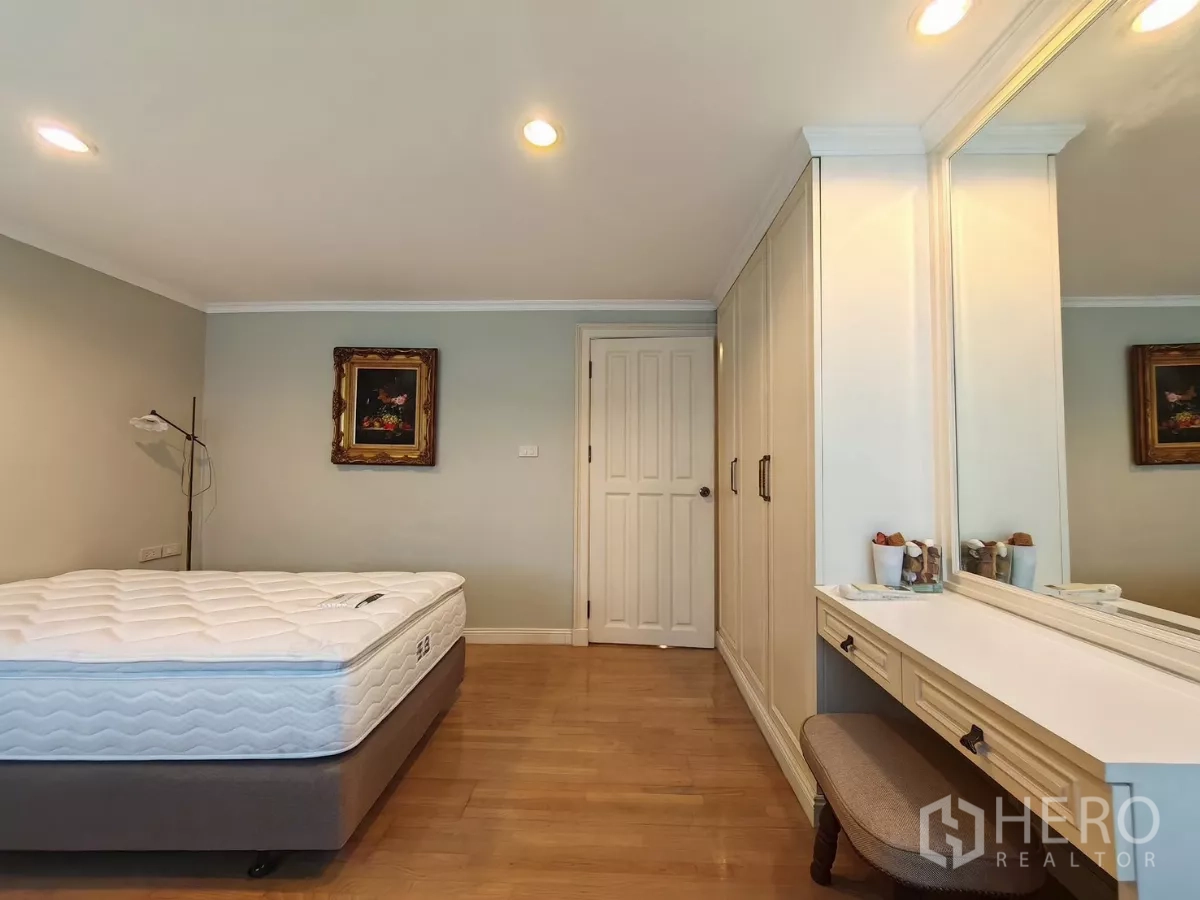 Condominium for rent in Pathum Wan, Bangkok - Bedroom view with mirrored vanity and full-height wardrobe.