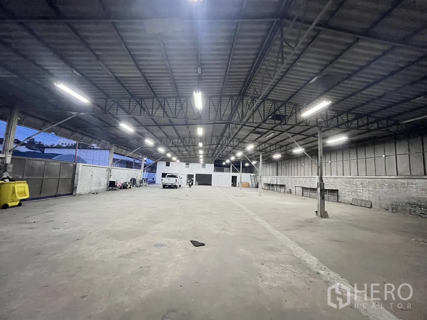 Warehouse for rent in Chatuchak, Bangkok - Large warehouse interior with metal truss roof, bright strip lighting, and concrete floor.