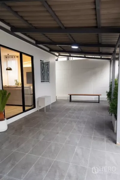 Detached House for rent in Huai Khwang, Bangkok - Covered patio and carport with gray floor tiles beside sliding glass door.