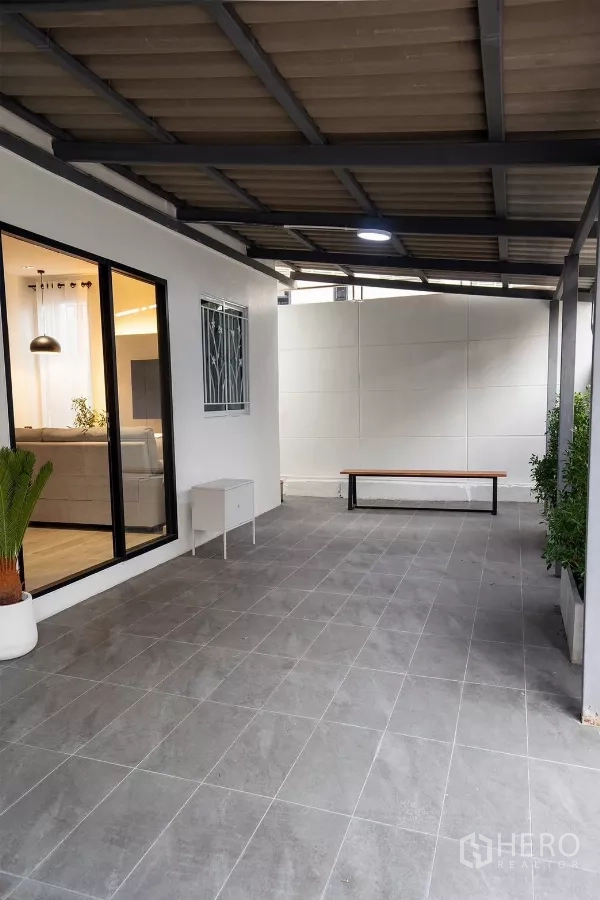 Detached House for rent in Huai Khwang, Bangkok - Covered patio and carport with gray floor tiles beside sliding glass door.
