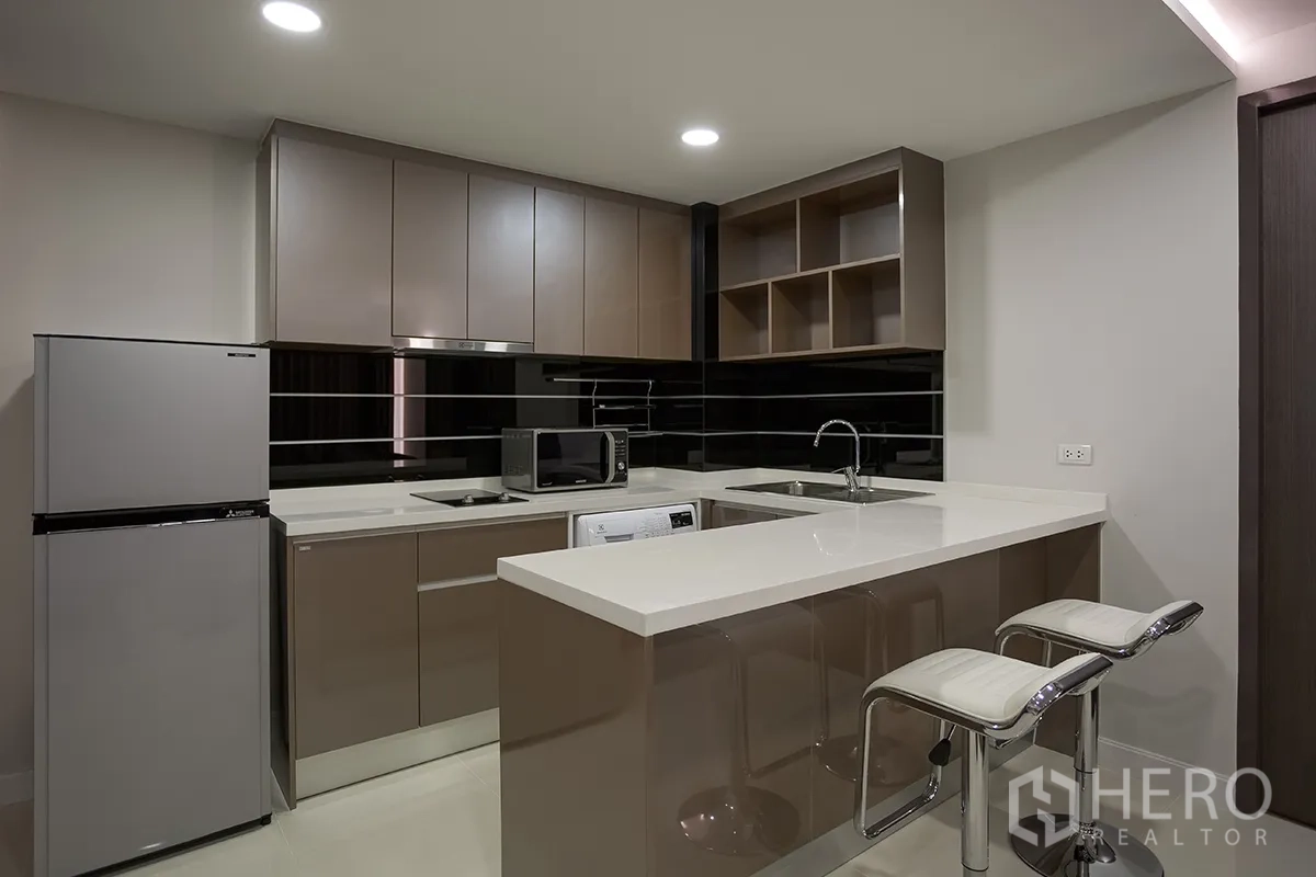 公寓 for rent in Khlong Toei, Bangkok - 现代厨房配备早餐吧、亮面柜体、冰箱、微波炉、水槽和洗衣机。