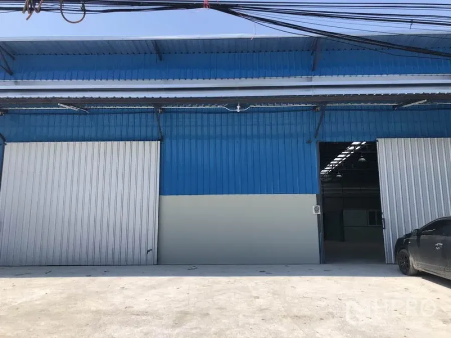 Warehouse for rent in Nonthaburi - Blue metal-clad warehouse exterior with wide sliding doors and loading apron in Pak Kret, Nonthaburi.