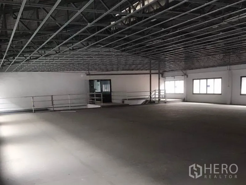 Factory for rent in Bang Bua Thong, Nonthaburi - Open upper production floor with metal truss ceiling, windows and safety railing.