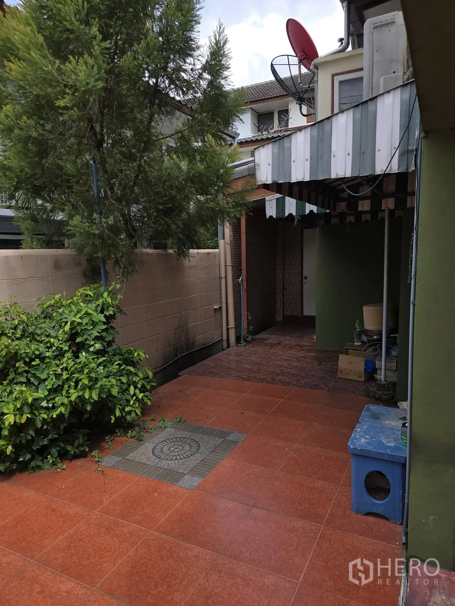 Home Office for rent in Wang Thonglang, Bangkok - Side patio with red tiles, small tree, boundary wall and metal awning.