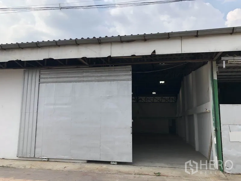 货栈 出租或出售在Khlong Luang, Pathum Thani - 仓库外立面，宽大金属滑门与遮檐装卸入口