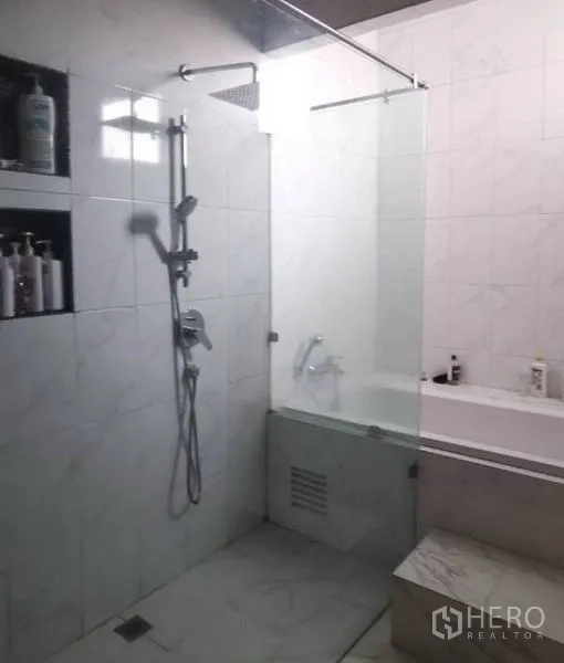 Detached House for sale in Pak Kret, Nonthaburi - Contemporary bathroom with glass-enclosed shower and bathtub in white marble-style tiles.
