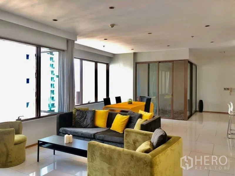 Condominium for sale in Khlong Toei, Bangkok - Open-plan living and dining area with full-height windows and a glass-enclosed study.
