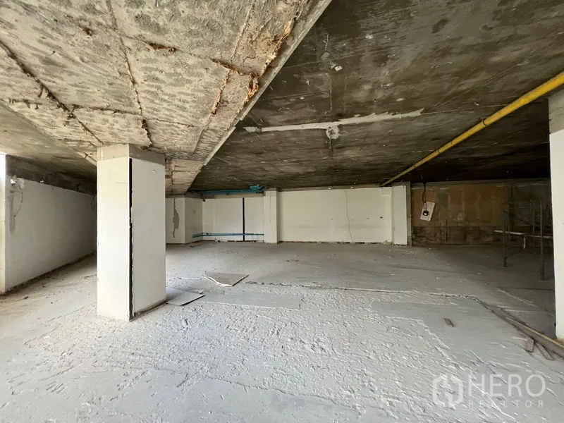 Retail Space for rent in Watthana, Bangkok - Raw retail space with exposed concrete ceiling, supporting pillars and blank walls.