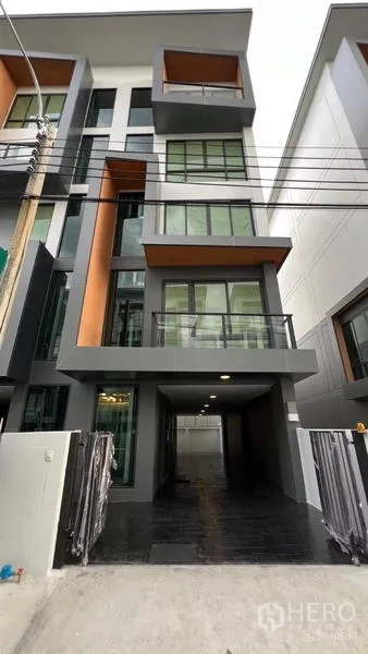 Home Office for rent - Modern four-storey home office facade with large windows, balconies and a covered driveway in Bang Kapi, Bangkok.